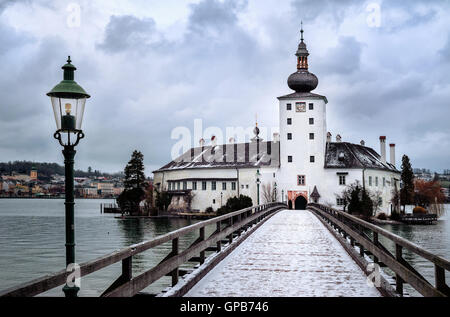 Schnee gedeckte Holzbrücke führt zu eine weiße Kirche auf einer Insel See in Gmunden in der Nähe von Salzburg, Österreich Stockfoto