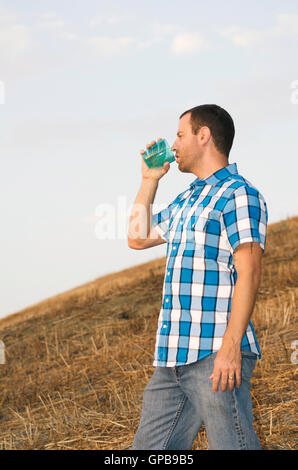 Mann steht auf einem Hügel außerhalb trinken aus einer Tasse trägt ein kariertes Hemd. Stockfoto