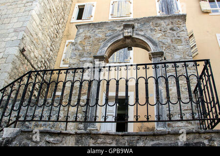 Alte Stadt von Budva, Montenegro - eine erhaltene Teil der mittelalterlichen Stadtmauer mit gewölbten Türen vor Gebäude aus dem 19. Jahrhundert Stockfoto