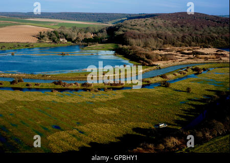 Der Fluß Cuckmere fließt durch die grünen und grünen Cuckmere Valley in Sussex nach heftigen Regenfällen und Überschwemmungen. Stockfoto