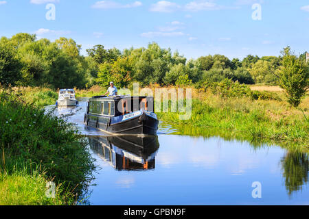 Narrowboat und Motor Boot gemächlich Cruisen auf den Wey Navigation in der Nähe von senden, Surrey an einem sonnigen Tag mit blauem Himmel im Sommer Stockfoto