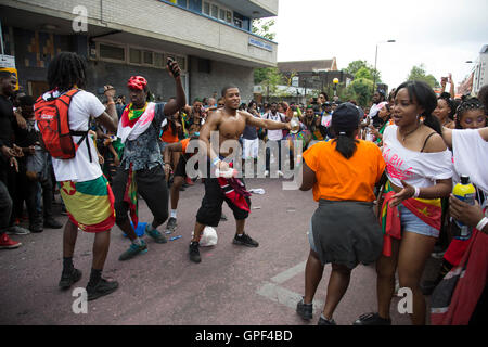 Bilden einen Kreis, die dann jeder stürzt in, in einer Explosion von fröhlichen Tanz auf Sonntag, 28. August 2016 bei den 50. Notting Hill Carnival in Westlondon. Ein Fest der Westindischen / Karibik Kultur und Europas größte Straßenparty, Festival und Parade. Nachtschwärmer kommen in hunderttausenden zum Spaß haben, tanzen, trinken und loslassen in die tolle Atmosphäre. Es wird geführt von den Mitgliedern der West-indischen / Karibische Gemeinschaft, besonders die Trinidad und Tobagonian britische Bevölkerung, von denen viele seit den 1950er Jahren in der Gegend gelebt haben. Der Karneval hat bis zu 2 Millionen angezogen. Stockfoto