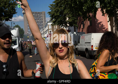 Gruppe von Freunden zu Fuß entlang Golborne Road mit Trellick Tower in der Ferne auf Sonntag, 28. August 2016 bei den 50. Notting Hill Carnival in Westlondon. Ein Fest der Westindischen / Karibik Kultur und Europas größte Straßenparty, Festival und Parade. Nachtschwärmer kommen in hunderttausenden zum Spaß haben, tanzen, trinken und loslassen in die tolle Atmosphäre. Es wird geführt von den Mitgliedern der West-indischen / Karibische Gemeinschaft, besonders die Trinidad und Tobagonian britische Bevölkerung, von denen viele seit den 1950er Jahren in der Gegend gelebt haben. Der Karneval hat bis zu 2 Millionen Menschen angezogen. Stockfoto