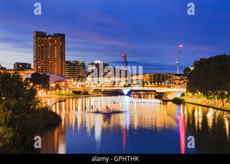 Stadt Adelaide CBD bei Sonnenaufgang Blick über Torrens River Park Fußgängerbrücke. Beleuchtete moderne Stadtgebäude reflektieren Stockfoto