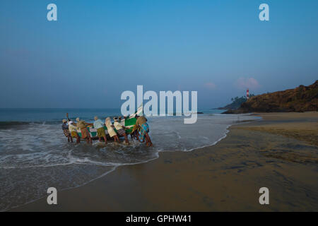 Fischer, die traditionelles Boot schieben. Gesehen bei Vizhinjam Beach, Kerala, Indien, Asien Stockfoto