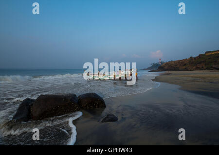 Fischer, die traditionelles Boot schieben. Gesehen bei Vizhinjam Beach, Kerala, Indien, Asien Stockfoto