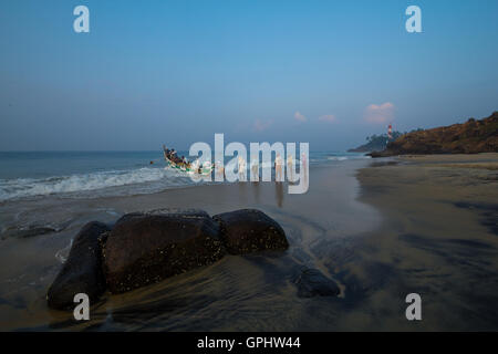 Fischer, die traditionelles Boot schieben. Gesehen bei Vizhinjam Beach, Kerala, Indien, Asien Stockfoto