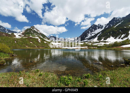 Sommerlandschaft Kamtschatkas: schöne Aussicht auf die Bergkette Vachkazhets, Bergsee und Wolken am blauen Himmel an sonnigen Tag. Stockfoto