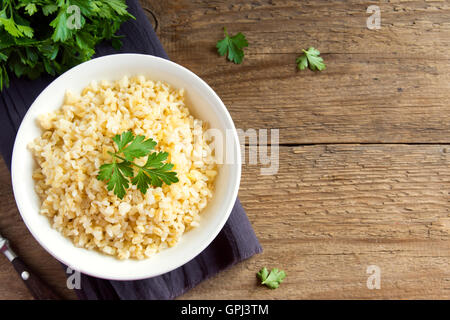 Bio Bulgur Weizenkorn in weiße Schüssel auf hölzernen Hintergrund mit Textfreiraum, gesunde vegetarische Ernährung Stockfoto