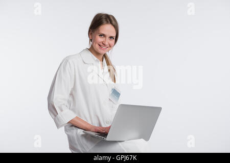 Lächelnd Ärztin arbeitet auf ihrem Laptop vor einem weißen Hintergrund Stockfoto