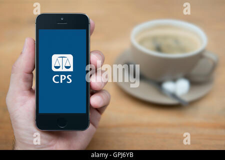 Ein Mann schaut auf seinem iPhone die UK Regierung Crown Prosecution Service Logo, mit Kaffee (nur zur redaktionellen Verwendung) anzeigt. Stockfoto