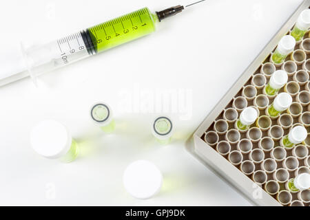 Über Ansicht geladen Spritze und Ampullen mit grüner Flüssigkeit auf eine weiße Labortisch Stockfoto