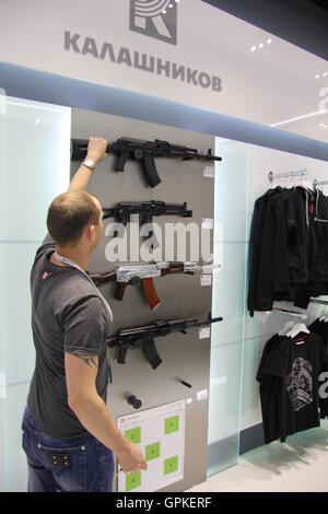 Moskau, Russland. 26. August 2016. Ein Verkäufer zeigt eine gefälschte Sturmgewehr AK-47 bei einer Kalaschnikow-Shop am Flughafen Scheremetjewo in Moskau, Russland, 26. August 2016. Im Store bietet das Unternehmen Bekleidung und Zubehör Alongise auch originalgetreue Nachbildung Waffen der klassischen AK-47-Waffe. Kalaschnikow ist Russlands größter Hersteller des weltweit verwendeten Waffen. Aber es gibt tatsächliche Gewehre Availabe in den Souvenir-Shop. T-Shirts mit Unternehmens-Logo und Warm-outdoor-Bekleidung mit Camouflage-Muster sind jedoch verfügbar. Foto: Thomas Koerbel/Dpa/Alamy Live News Stockfoto