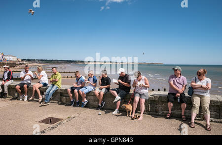 Touristen sitzen am Deich Bridlington East Yorkshire UK Stockfoto