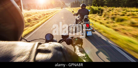 Motorradfahrer fahren auf der Autobahn im schönen Abendlicht. Schuss aus Fahrersicht Sozius Stockfoto
