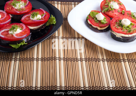 Hausgemachte vegetarische Gerichte von geschmorte Auberginen und frischen Tomaten auf zwei Teller mit Bambus Matte Nahaufnahme Stockfoto