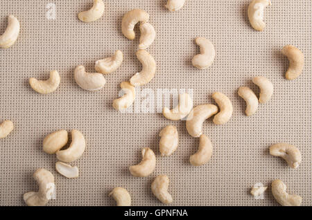 Rohe Cashewnüsse verstreut auf der Oberfläche des Tisches auf dem Hintergrund des Gewebes Stockfoto