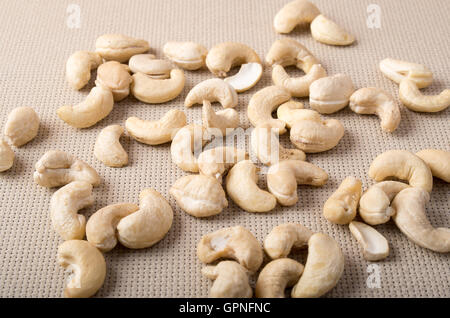 Detailansicht auf rohe Cashewnüsse verstreut auf der Oberfläche des Tisches auf dem Hintergrund des Gewebes Stockfoto