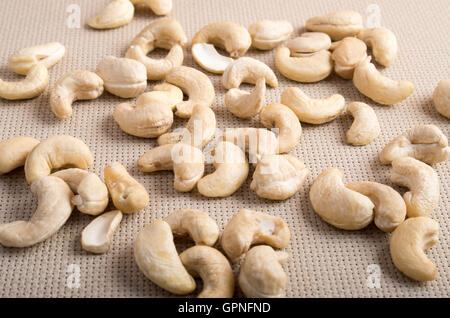 Detailansicht auf rohe Cashewnüsse verstreut auf der Oberfläche des Tisches auf dem Hintergrund des Gewebes Stockfoto