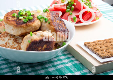 Hausgemachte gebratene Fleischbällchen in einer Schüssel weiß, Salat von rohem Gemüse und Vollkorn Zwieback auf einer grünen Tischdecke Stockfoto