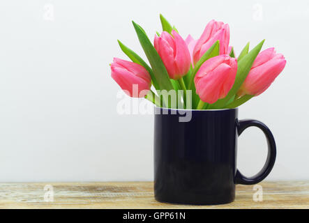 Rosa Tulpen in dunkelblauen Becher auf rustikale Oberfläche mit Textfreiraum Stockfoto