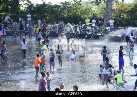 Kinder und Erwachsene gleichermaßen erfrischen Sie sich während der Hitzewelle im Sommer 2016 am LeFrak Center am See Sommer-Wasserpark im Prospect Park, Brooklyn, NY. Stockfoto