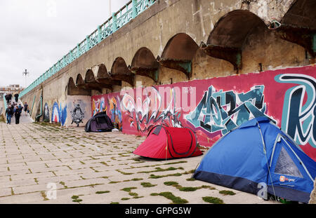 Tribut-Graffiti-Kunst zu einem Mod auf einem Roller durch Künstler Jef Aerosol entlang der Bögen auf Brighton Seafront mit Obdachlosen Zelte Stockfoto