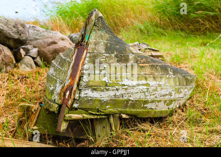 Sehr alte Fäulnis Boot liegend auf trockenem Land verschwenden. Natur ist das Material in das verlassene Schiff langsam zurück. Stockfoto