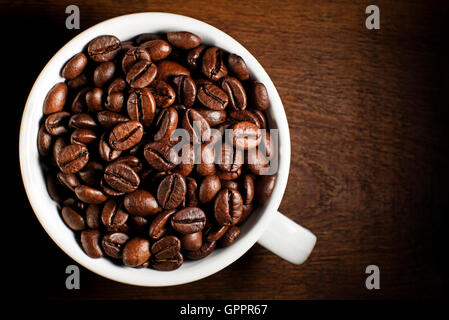 Frische Kaffeebohnen im Cup auf hölzernen Hintergrund Stockfoto