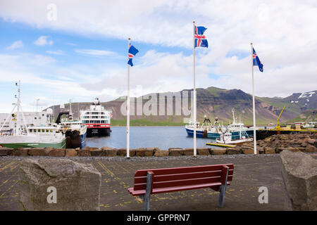 Isländische Fahnen auf dem Kai mit Fischerbooten und einem Kreuzfahrtschiff vor Anker im Hafen. Grundarfjordur Snaefellsnes Island Stockfoto