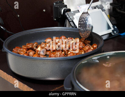 Gebratene Kastanien in einer Pfanne zum Kochen. Streetfood Stockfoto