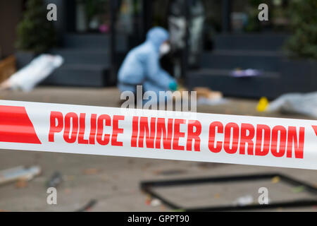 Polizei innere cordon Band Barriere und eine Szene des Verbrechens Officer / Offiziere & Beweise Identifikation Zahl Marker / Marker. UK Stockfoto