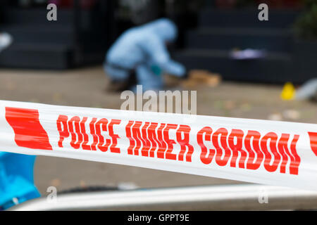 Polizei innere cordon Band Barriere und eine Szene des Verbrechens Officer / Offiziere & Beweise Identifikation Zahl Marker / Marker. UK Stockfoto