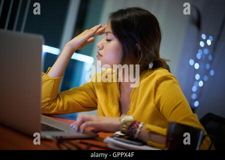 Junge Frau mit Laptop-Computer für die Hausaufgaben. Müde, hispanischen Mädchen und Hochschulausbildung. Weibliche Studenten studieren und mit pc Stockfoto