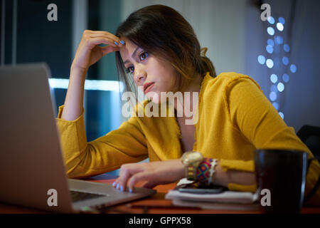 Junge Frau mit Laptop-Computer für die Hausaufgaben. Müde, hispanischen Mädchen und Hochschulausbildung. Weibliche Studenten studieren und mit pc Stockfoto