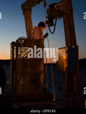 Ein Fischer entlädt sich sein Boot an der Anlegestelle der Stadt auf einem Dezemberabend in Bar Harbor, Maine. Stockfoto