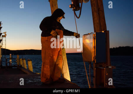 Ein Fischer entlädt sich sein Boot an der Anlegestelle der Stadt an einem kalten Dezemberabend in Bar Harbor, Maine. Stockfoto