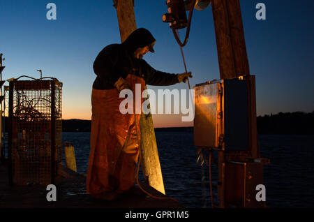 Ein Fischer entlädt sich sein Boot an der Anlegestelle der Stadt an einem kalten Winterabend in Bar Harbor, Maine. Stockfoto