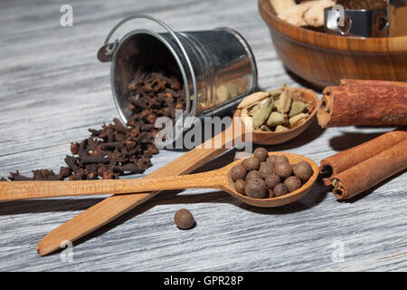 Kardamom, Nelken und Pfeffer in Löffel auf Holz Stockfoto