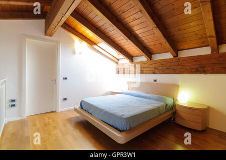 Gemütlichen Dachboden Schlafzimmer mit Holzboden und Decke mit sichtbaren Balken Stockfoto