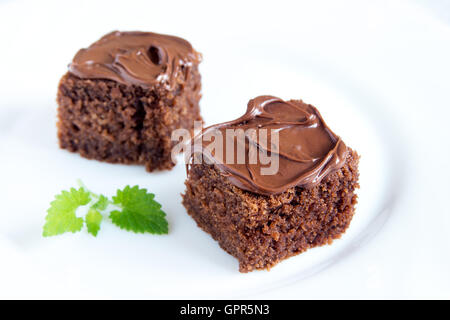 Schokolade Mini-Kuchen mit Schokoladenglasur und Minze auf weißen Teller hautnah Stockfoto