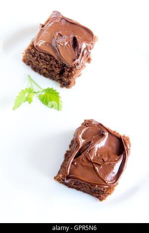 Schokolade Mini-Kuchen mit Schokoladenglasur und Minze auf weißen Teller hautnah Stockfoto