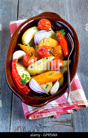 Rustikalen Ofen gebackenes Gemüse mit Gewürzen und Kräutern in Auflaufform hautnah, vegetarische Bio-Mahlzeit Stockfoto