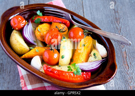 Rustikalen Ofen gebackenes Gemüse mit Gewürzen und Kräutern in Auflaufform hautnah, vegetarische Bio-Mahlzeit Stockfoto