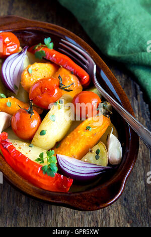 Rustikalen Ofen gebackenes Gemüse mit Gewürzen und Kräutern in Auflaufform hautnah, vegetarische Bio-Mahlzeit Stockfoto