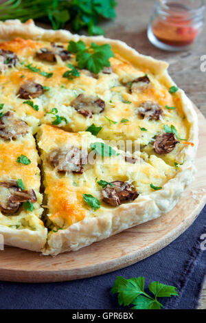 Hausgemachte französische Quiche Kuchen mit Pilzen (Champignons) und Käse über rustikalen hölzernen Hintergrund hautnah Stockfoto