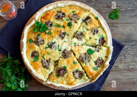 Hausgemachte französische Quiche Kuchen mit Pilzen (Champignons) und Käse über rustikale Holz Hintergrund Stockfoto