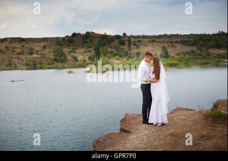 schöne junge Paare, die nahe dem See am Tag Hochzeit Stockfoto