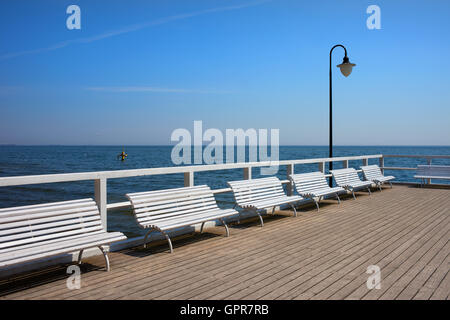 Weiße Bänke auf hölzernen Pier am Ostsee in Gdynia Orlowo, Polen, Sommerurlaub Stockfoto