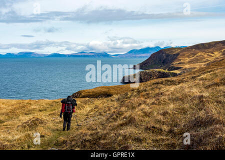 Ein Wanderer auf der Küstenstraße Track von Guirdil Bay, Glen Shellesder, Isle Of Skye in der Ferne, Isle of Rum, Scotland, UK. Stockfoto